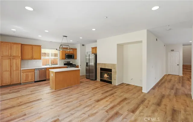a view of kitchen with stainless steel appliances granite countertop a stove top oven a sink dishwasher and a fireplace with wooden floor
