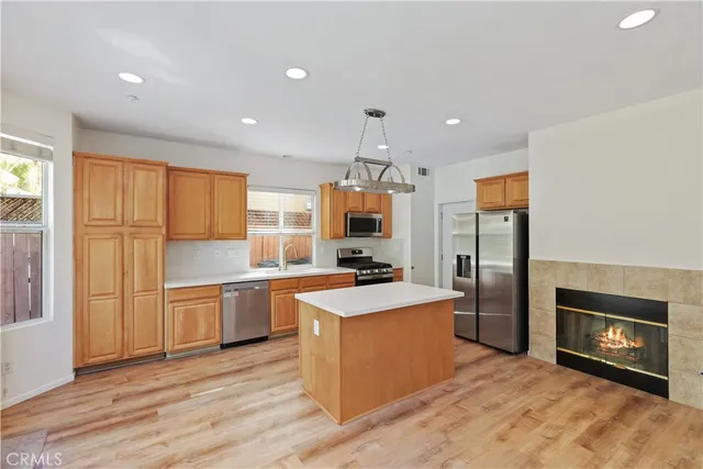 a kitchen with stainless steel appliances granite countertop a stove top oven a refrigerator a sink and dishwasher with wooden floor