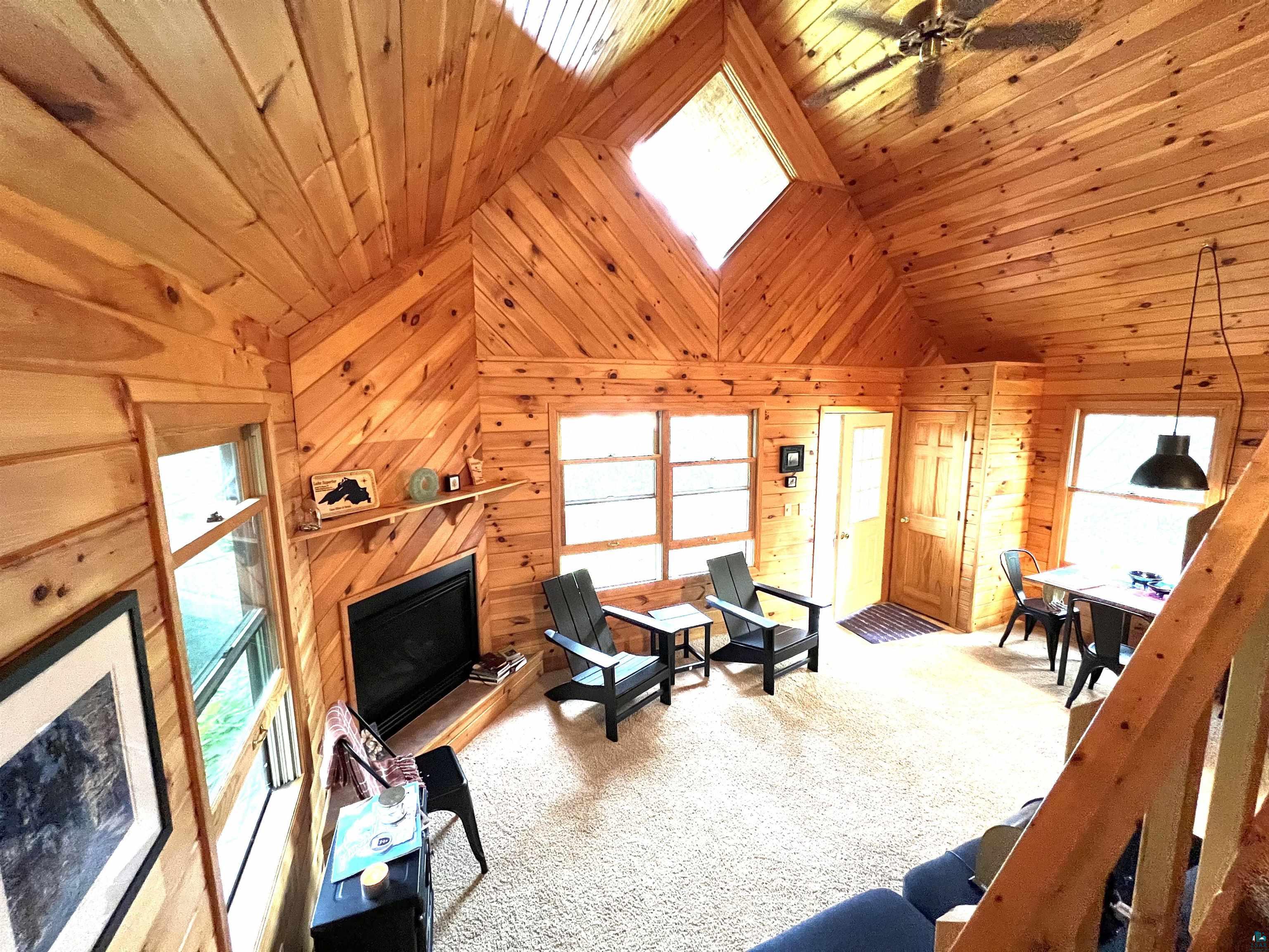 4366 Wood Ridge Drive Two Harbors, MN 55616 - Photo 11 of 21 Living room with ceiling fan, wood ceiling, light carpet, and wooden walls