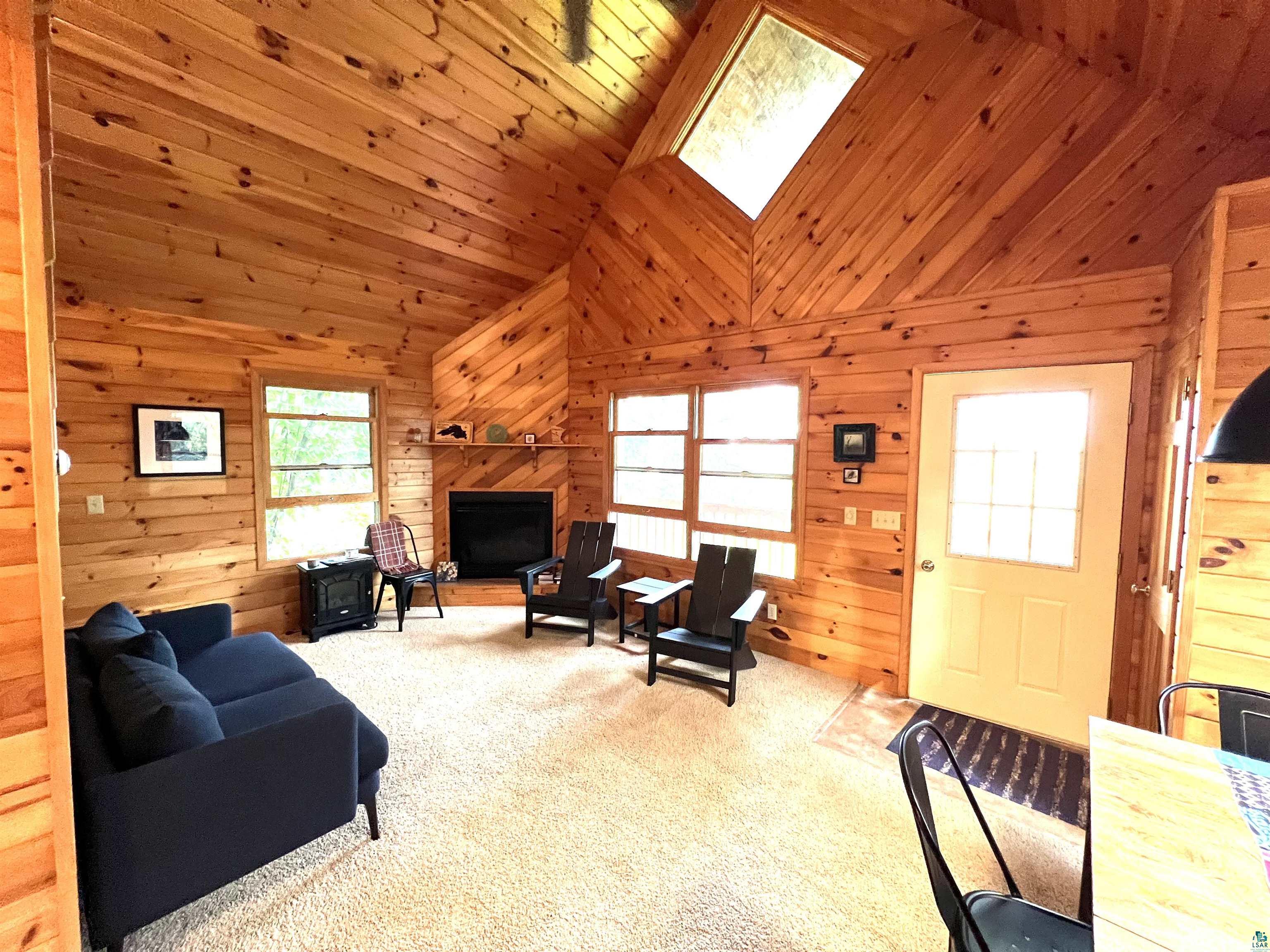 4366 Wood Ridge Drive Two Harbors, MN 55616 - Photo 4 of 21 Living room featuring carpet flooring, wood walls, and a skylight