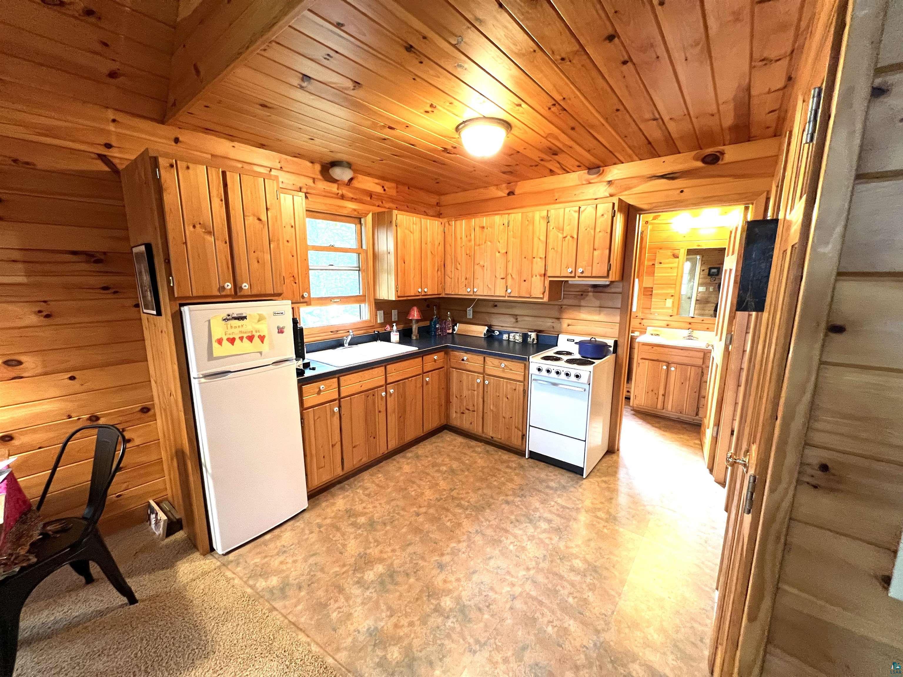 4366 Wood Ridge Drive Two Harbors, MN 55616 - Photo 6 of 21 Kitchen with sink, wooden walls, and white appliances
