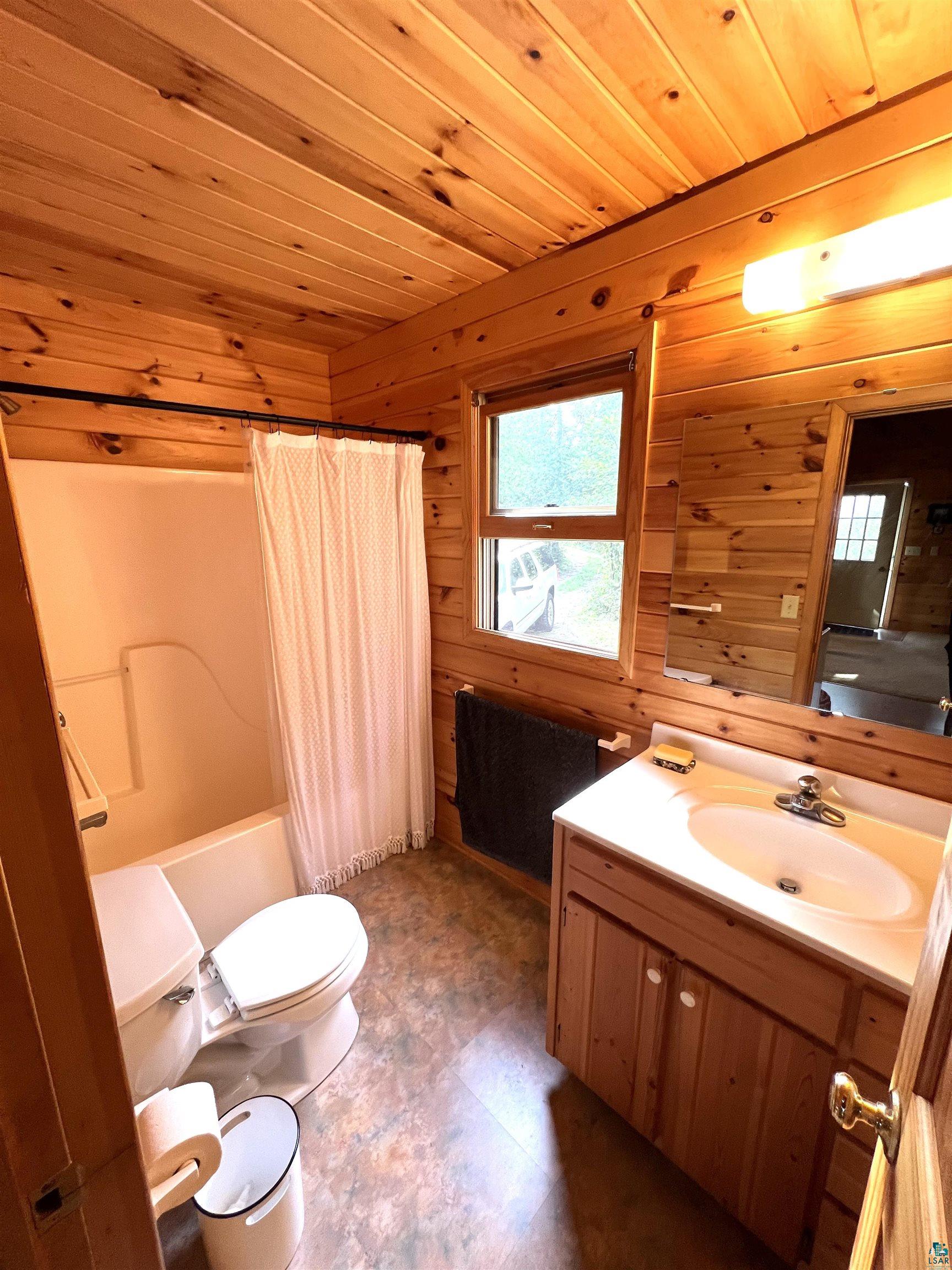 4366 Wood Ridge Drive Two Harbors, MN 55616 - Photo 7 of 21 Bathroom featuring wood ceiling, toilet, tile patterned flooring, wooden walls, and vanity