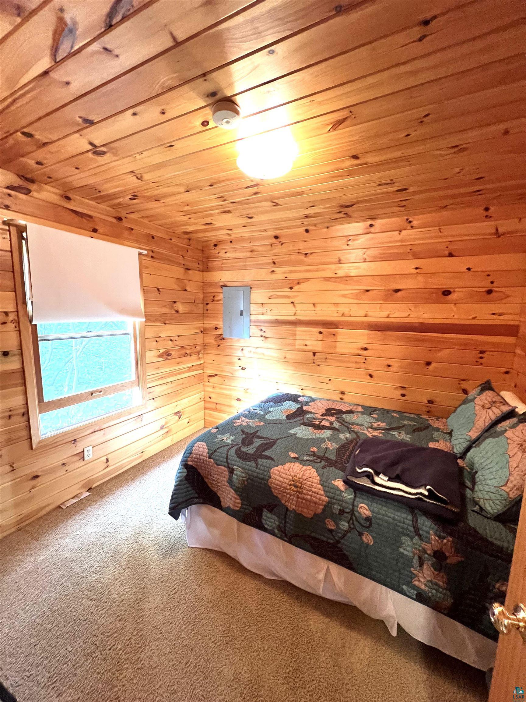 4366 Wood Ridge Drive Two Harbors, MN 55616 - Photo 9 of 21 Bedroom featuring wood walls, carpet floors, and wooden ceiling