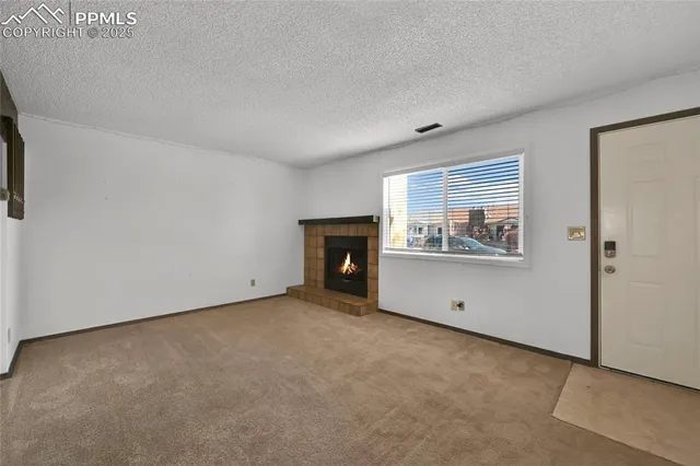 a view of an empty room with a fireplace and window