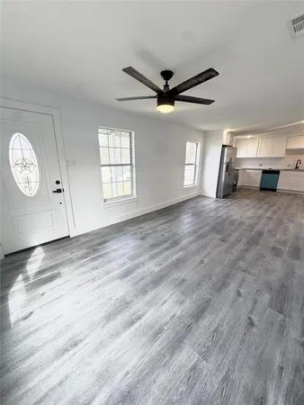 a view of empty room with wooden floor and fan