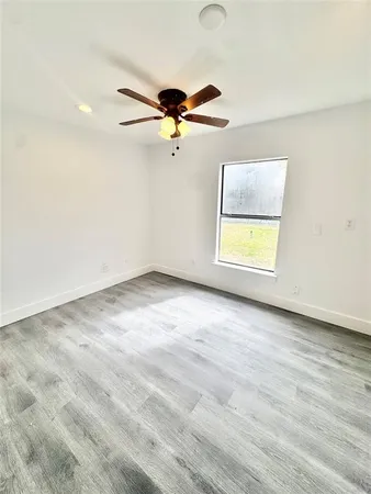 an empty room with a window and a ceiling fan