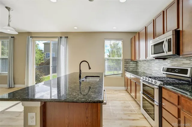a kitchen with stainless steel appliances granite countertop a sink and dishwasher a stove top oven with wooden floor