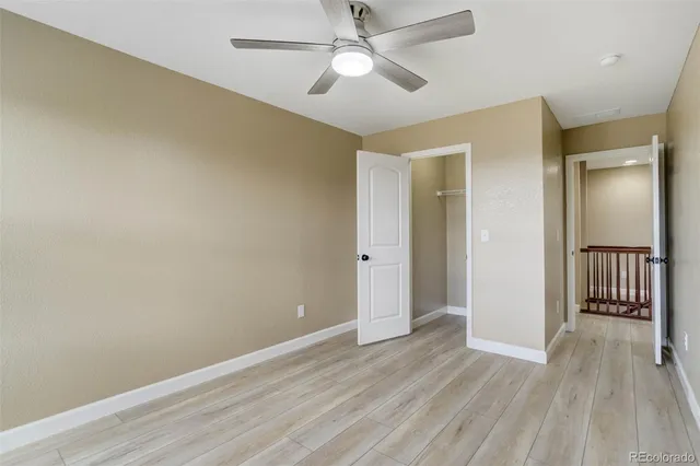 an empty room with wooden floor a ceiling fan and closet