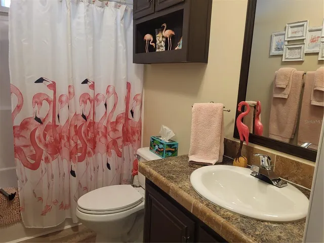 a bathroom with a granite countertop toilet sink and mirror