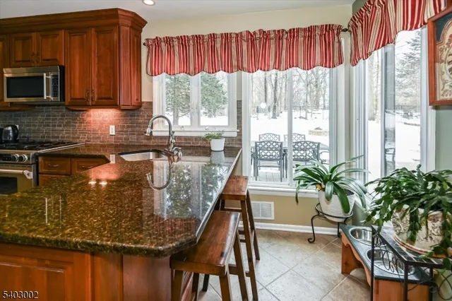 a large kitchen with stainless steel appliances granite countertop a stove a sink and a microwave