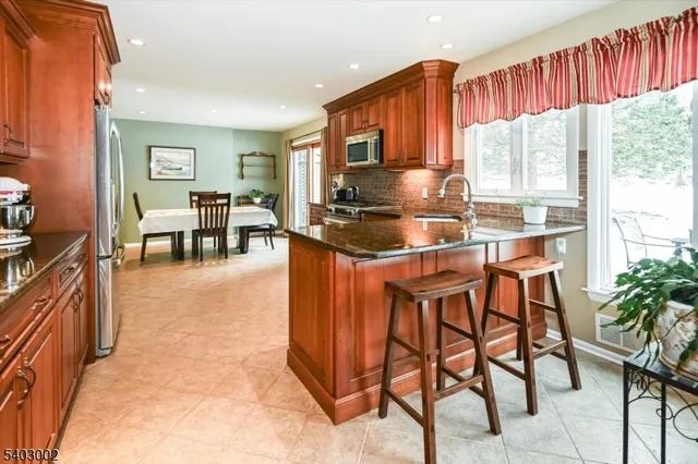 a kitchen with stainless steel appliances granite countertop table chairs and a refrigerator