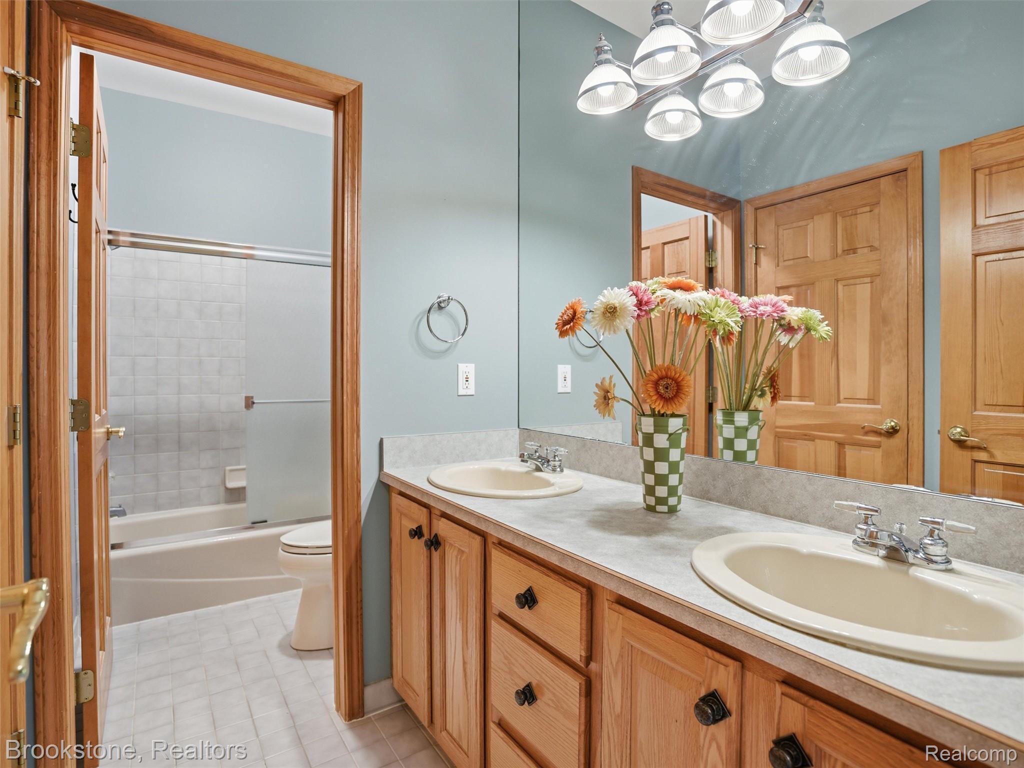 9523 Quail Ridge Run Brighton, MI 48114 - Photo 31 of 50 Bathroom featuring a dual vanity with light wood cabinetry, oval undermount sinks, chrome faucets, and a full-width mirror