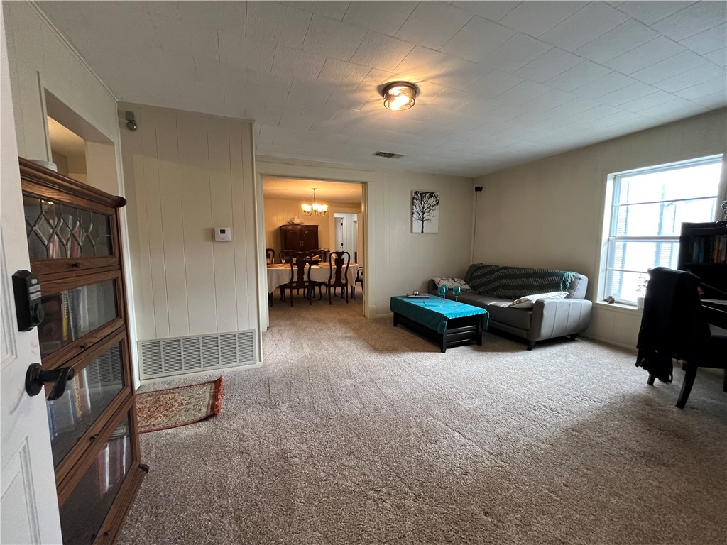 1102 North Travis Avenue Cameron, TX 76520 - Photo 9 of 48 Living area with carpet floors, a chandelier, and wood walls