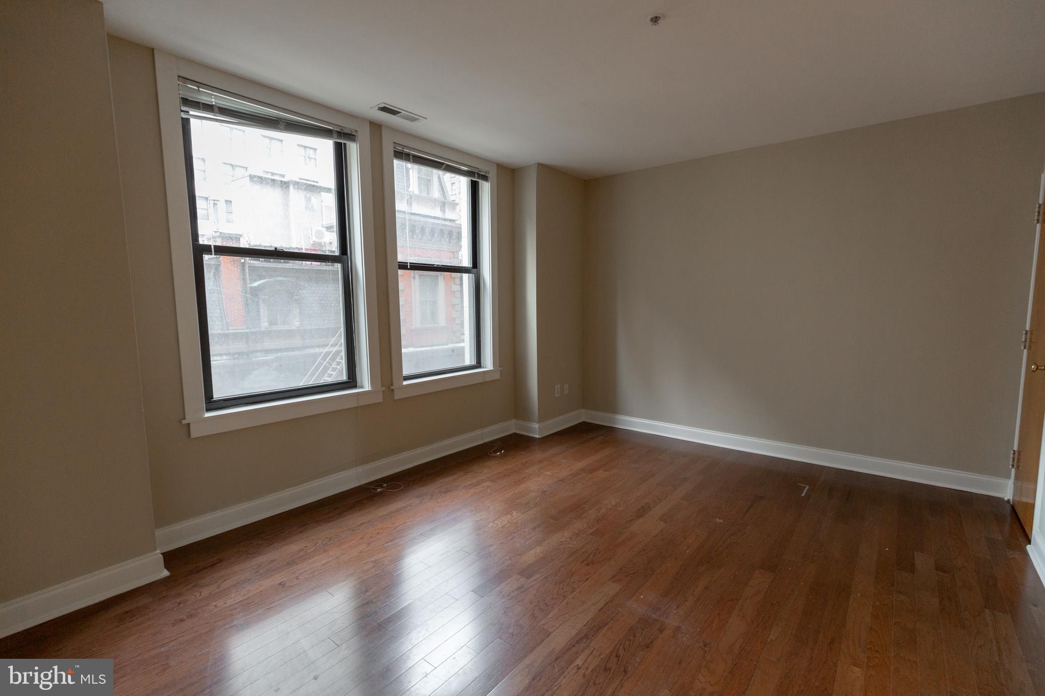 1411-1 Walnut Street, Unit 1005 Philadelphia, PA 19102 - Photo 19 of 27 an empty room with wooden floor and windows