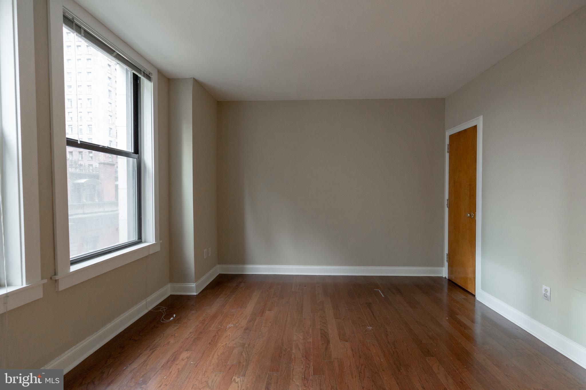 1411-1 Walnut Street, Unit 1005 Philadelphia, PA 19102 - Photo 20 of 27 an empty room with wooden floor and windows