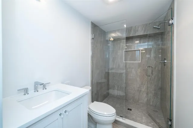 a bathroom with a shower sink vanity mirror and toilet
