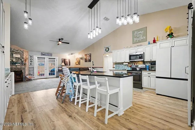 a kitchen with stainless steel appliances kitchen island granite countertop a table chairs and a refrigerator
