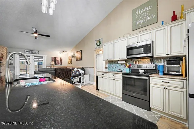 a kitchen with stainless steel appliances granite countertop a sink dishwasher stove and white cabinets