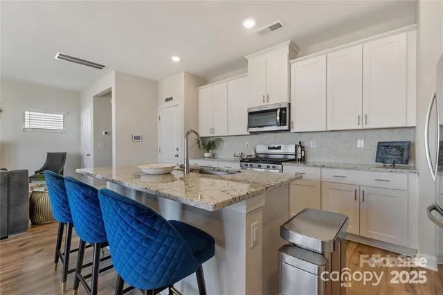 a kitchen with stainless steel appliances granite countertop a sink a stove a refrigerator a microwave and dining table