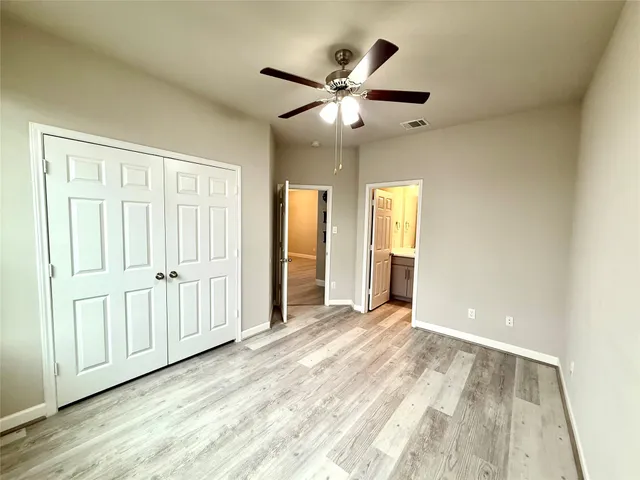 an empty room with wooden floor chandelier fan and windows