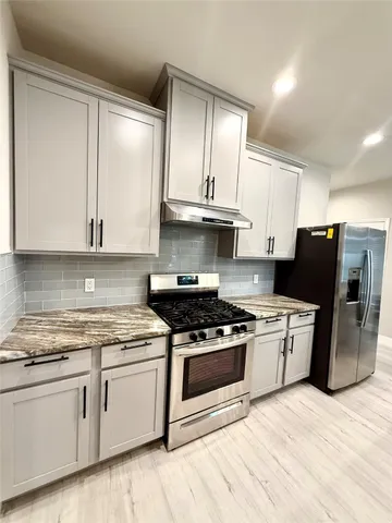 a large kitchen with stainless steel appliances granite countertop a stove and a sink