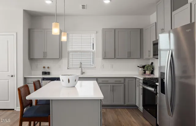 a kitchen with a sink a microwave a refrigerator and white cabinets