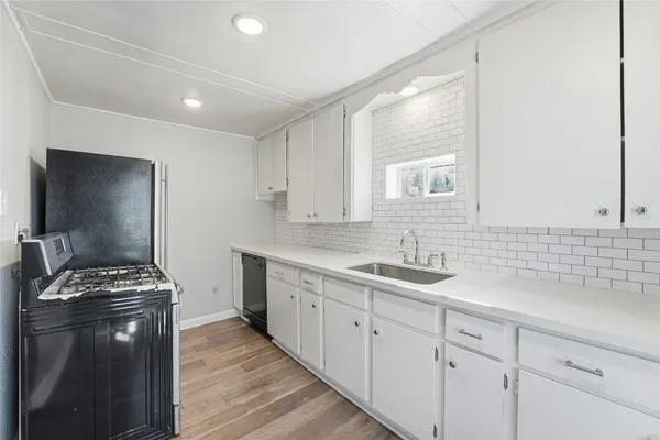 a kitchen with sink a stove and cabinets