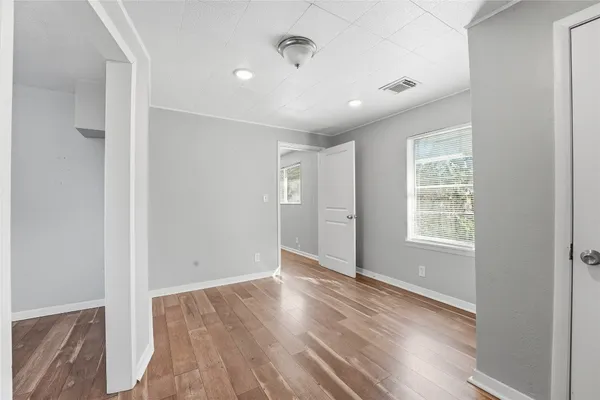 a view of an empty room with wooden floor and a window