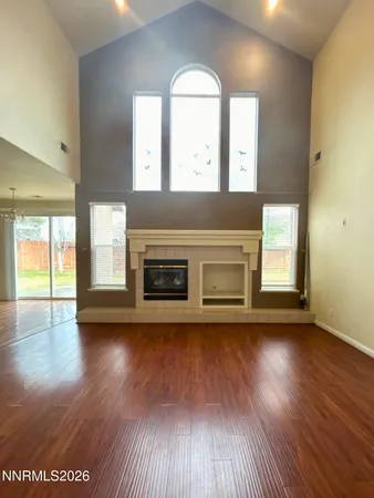 an empty room with wooden floor fireplace and windows