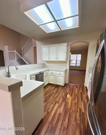a kitchen with a sink a stove cabinets and a wooden floor