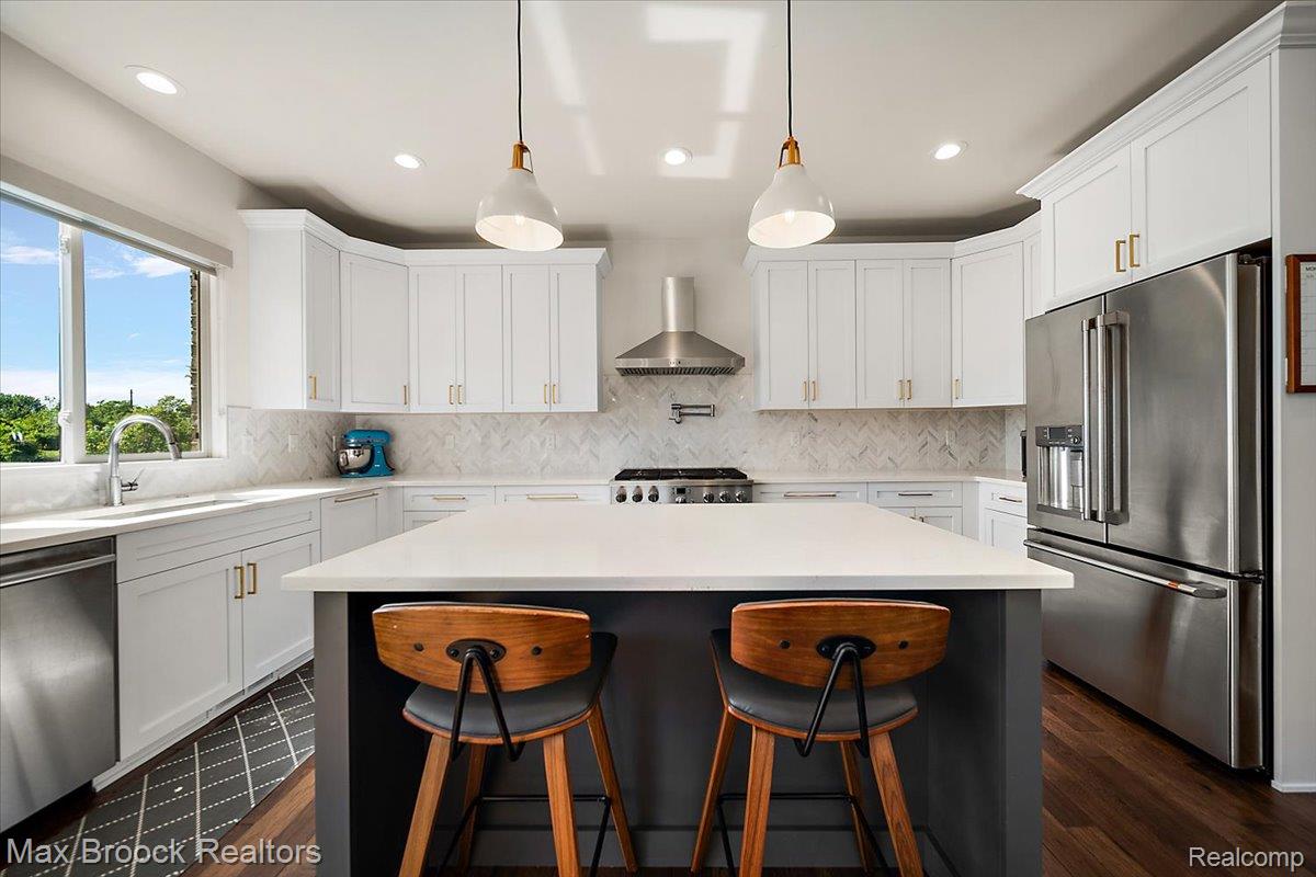 1942 Nottingham Drive Rochester, MI 48307 - Photo 25 of 97 Kitchen featuring a central island with countertop seating, white shaker cabinetry, stainless steel appliances, a chevron pattern tile backsplash, and recessed lighting