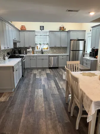 a kitchen with kitchen island granite countertop wooden floors and white stainless steel appliances