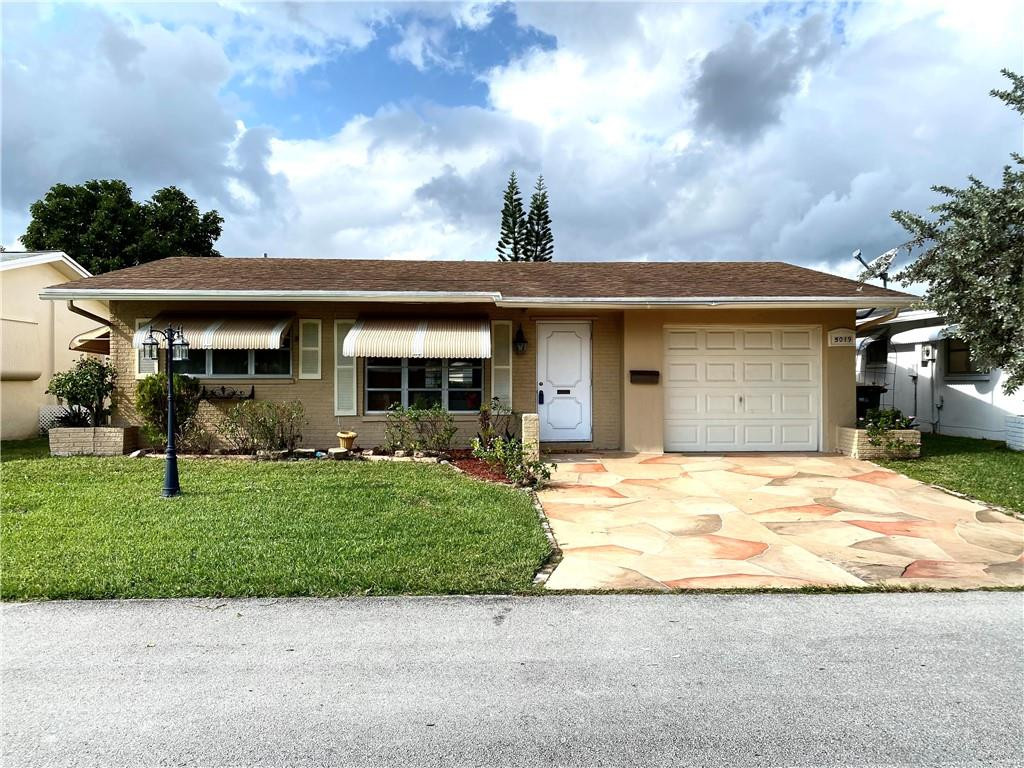 5019 Northwest 49th Road Tamarac, FL 33319 - Photo 1 of 25 a front view of a house with a garden and plants