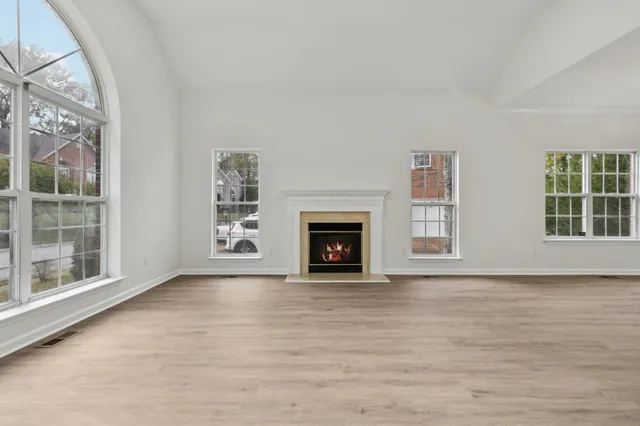 an empty room with windows fireplace and wooden floor