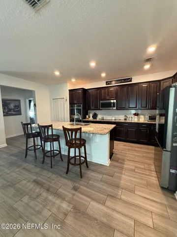 a kitchen with stainless steel appliances kitchen island granite countertop a table chairs sink and cabinets