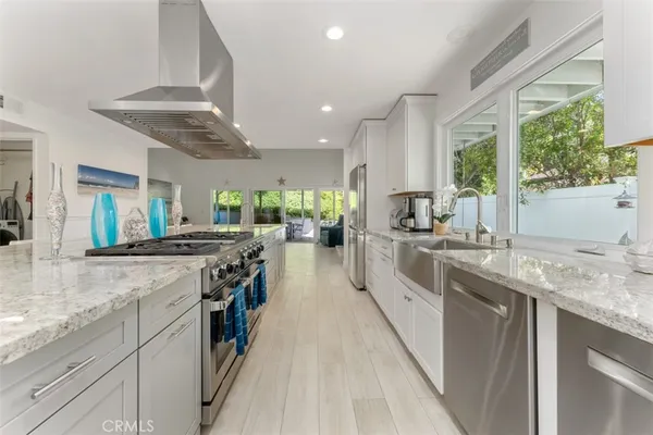 a kitchen with stainless steel appliances granite countertop hardwood floor sink stove and large window