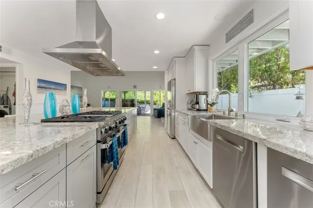 a kitchen with stainless steel appliances granite countertop hardwood floor sink stove and large window