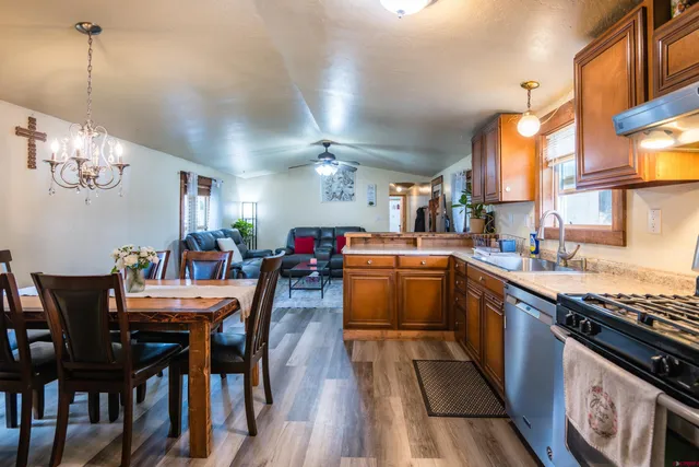 a kitchen with stainless steel appliances granite countertop a stove a sink dishwasher a dining table and chairs with wooden floor