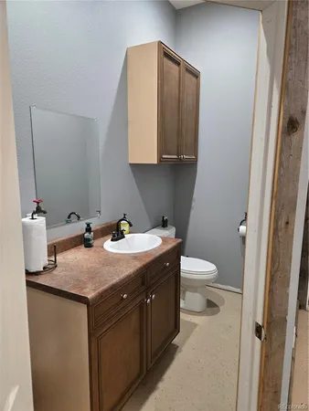 a bathroom with a granite countertop sink and a toilet