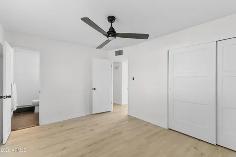 a view of empty room with wooden floor and fan