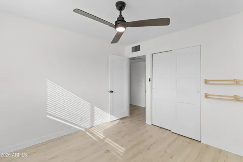 a view of empty room with wooden floor and fan