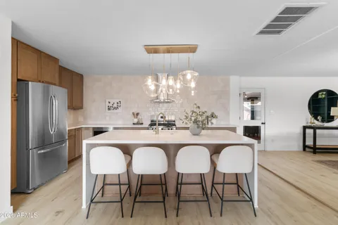 a living room with furniture a chandelier and a kitchen view