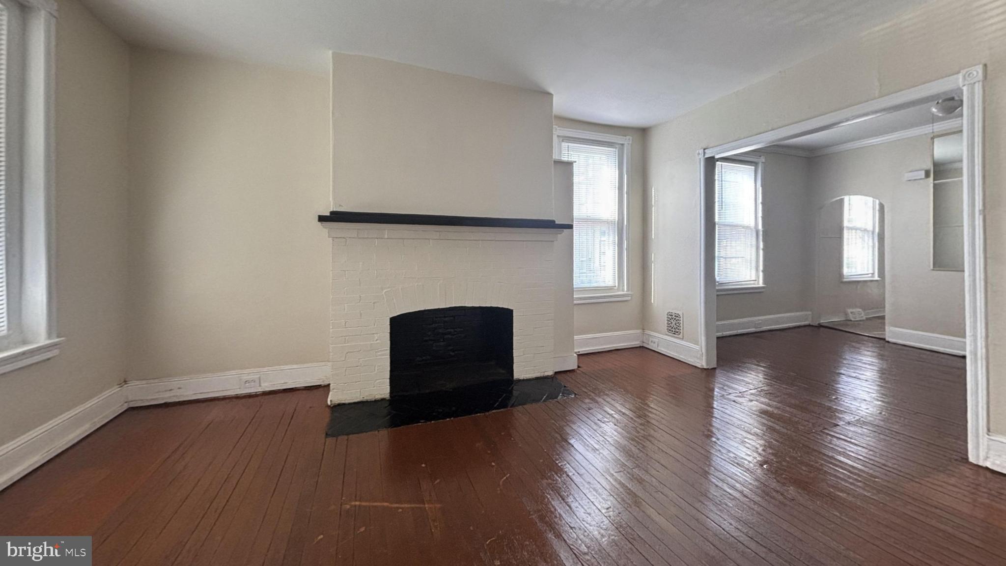 5471 Delancey Street Philadelphia, PA 19143 - Photo 2 of 9 an empty room with wooden floor and fireplace
