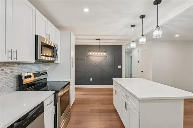a kitchen with cabinets stainless steel appliances and wooden floor