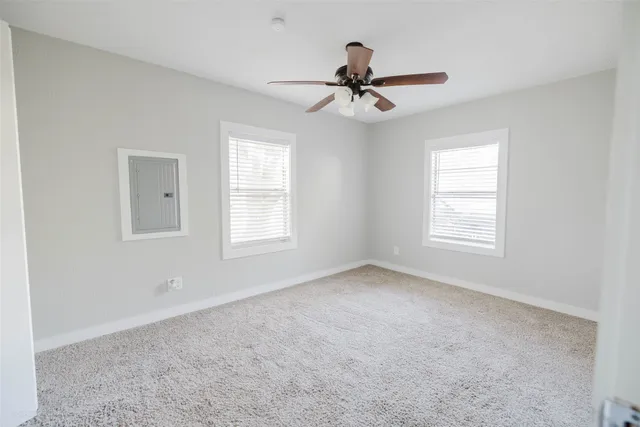 a view of a livingroom with a ceiling fan & windows