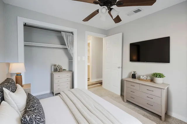 a bedroom with a bed and a flat tv screen on dresser