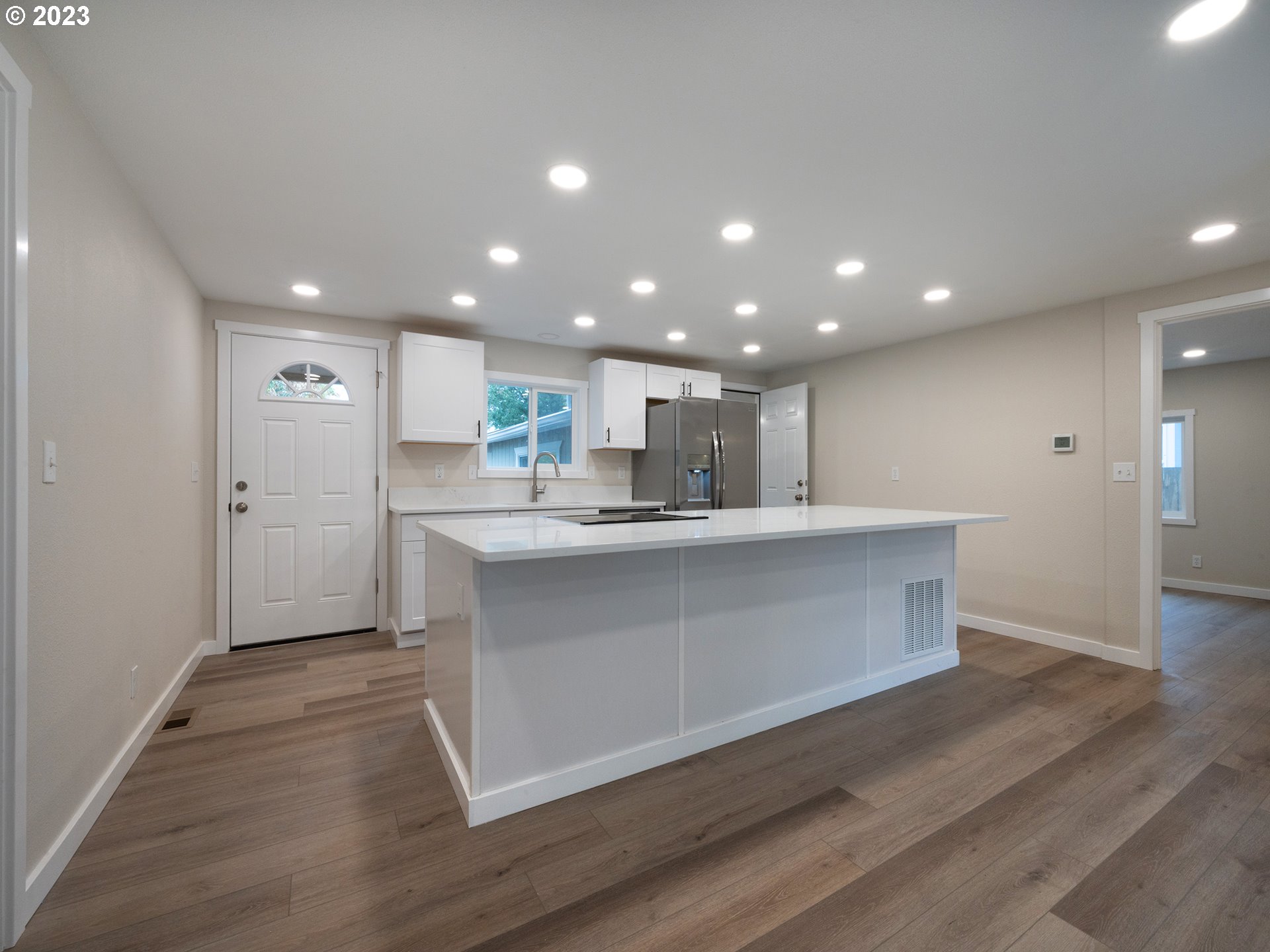 5131 Daisy Street Springfield, OR 97478 - Photo 6 of 45 a open kitchen with kitchen island a sink dishwasher a refrigerator and white cabinets with wooden floor