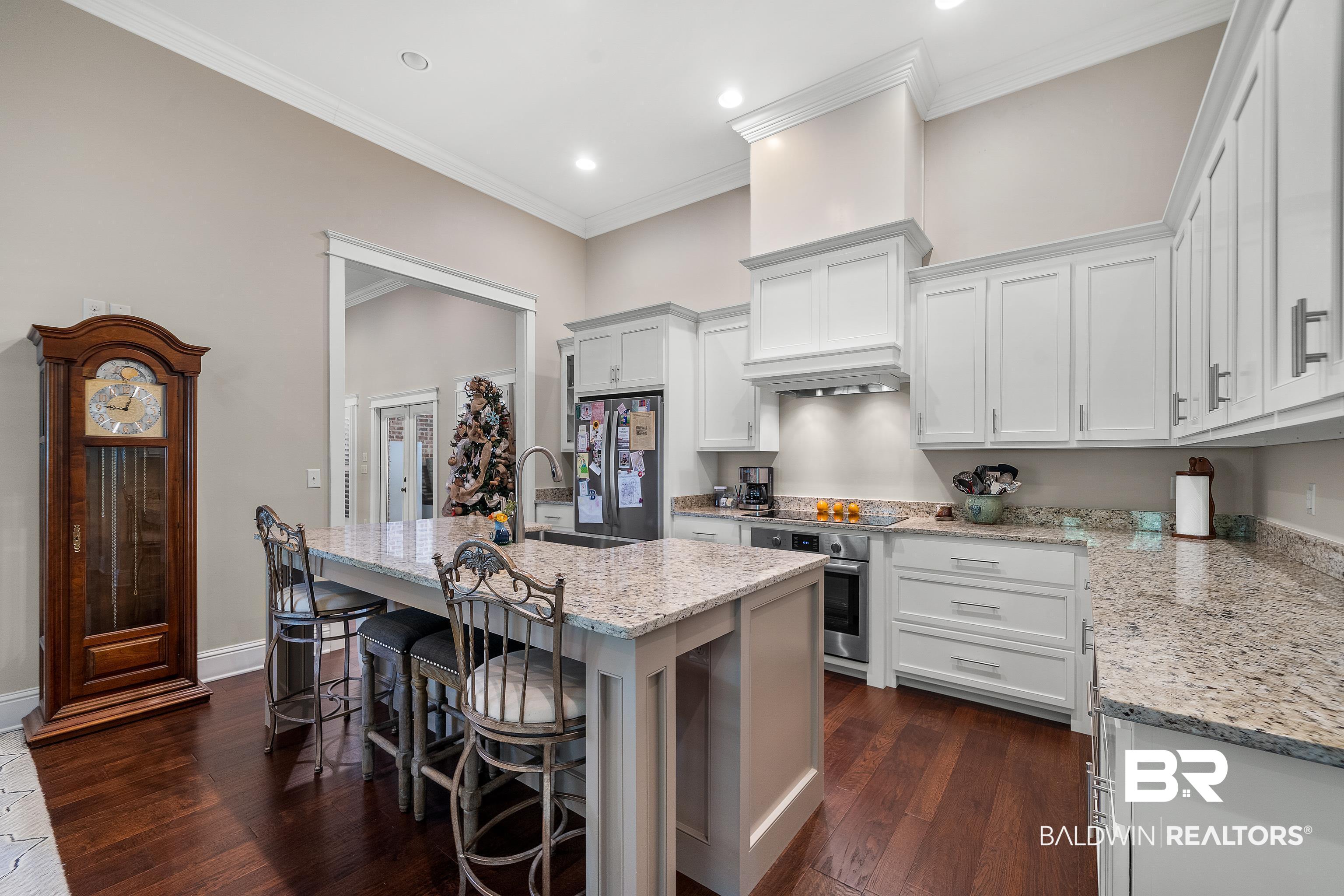 29530 St John Street Daphne, AL 36526 - Photo 9 of 38 Kitchen with light stone counters, dark hardwood / wood-style floors, white cabinetry, stainless steel appliances, and a center island with sink