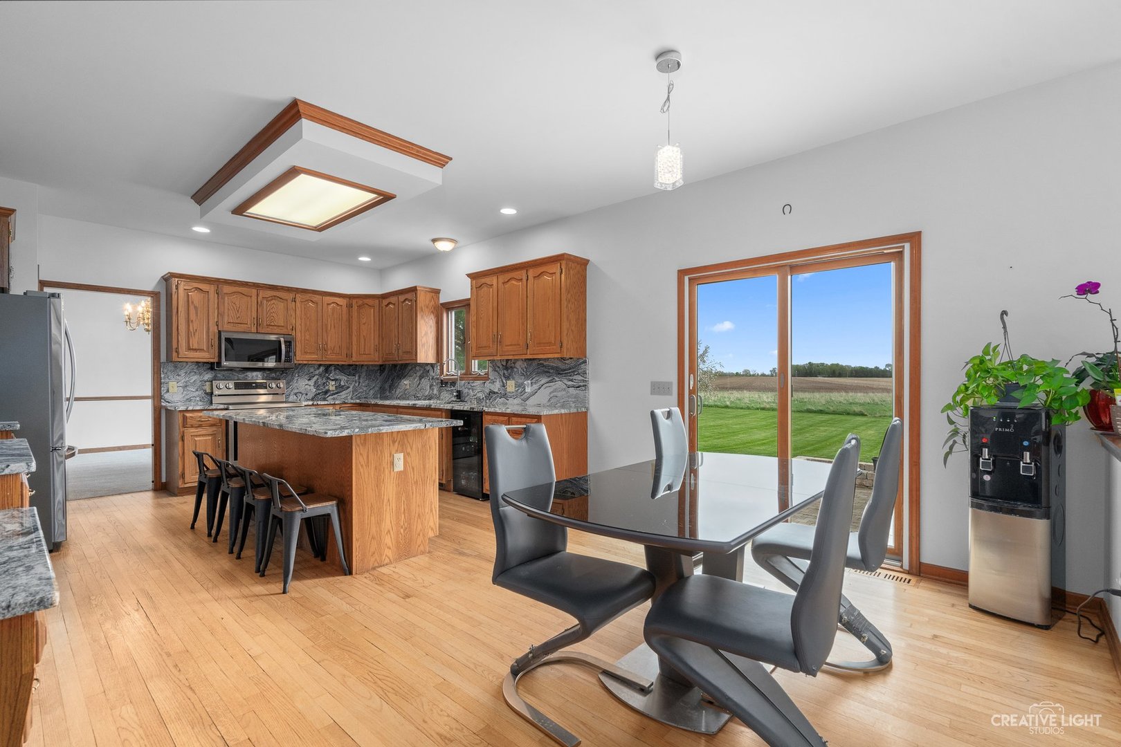 980 Eldamain Road Plano, IL 60545 - Photo 11 of 27 a kitchen with stainless steel appliances granite countertop a stove top oven a dining table and chairs with wooden floor