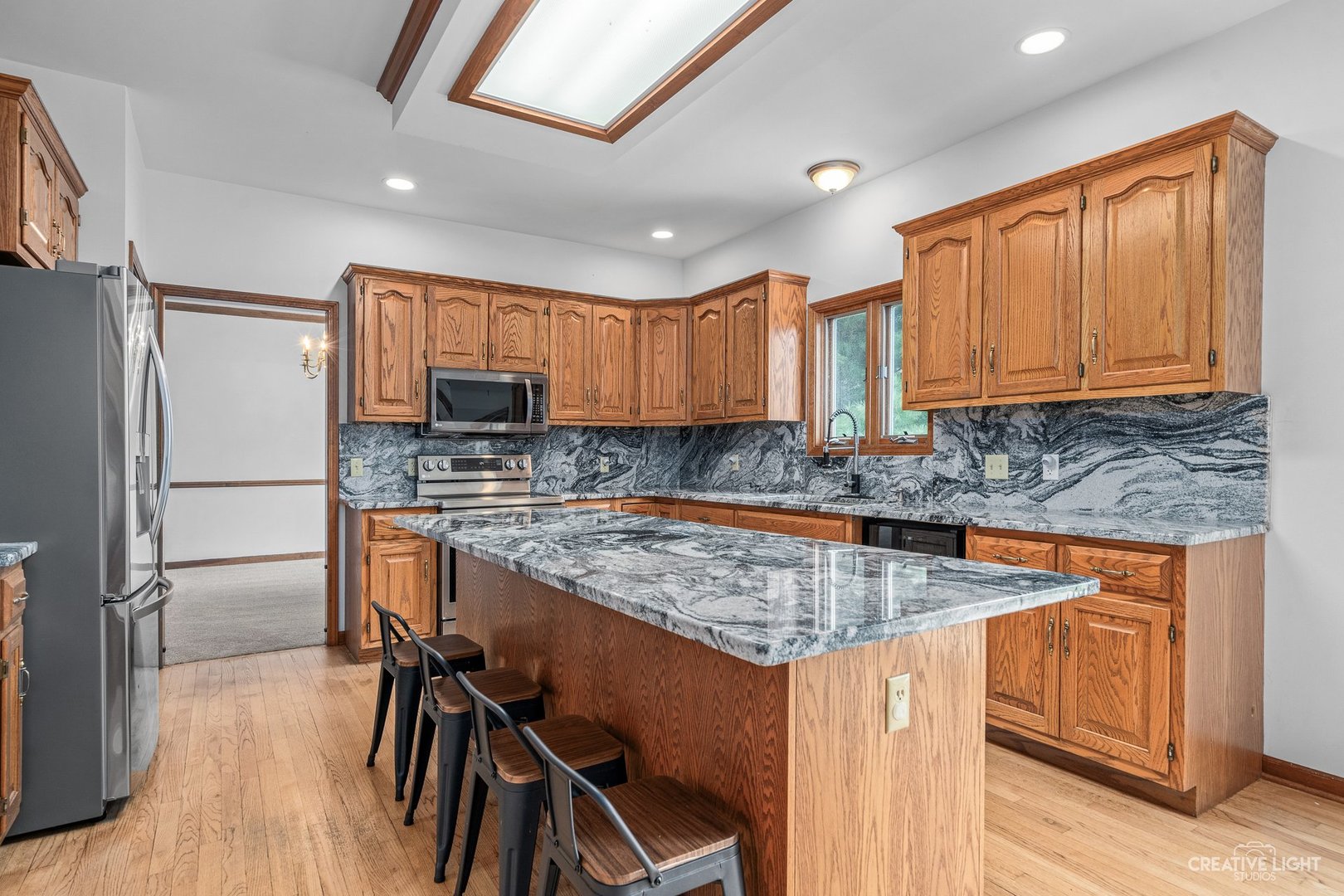 980 Eldamain Road Plano, IL 60545 - Photo 10 of 27 a kitchen with stainless steel appliances granite countertop wooden floor sink stove and refrigerator